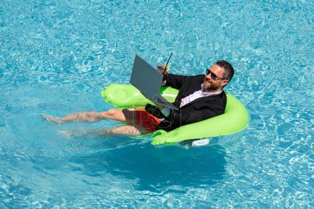 Photo for Business man in suit drink summer cocktail and using laptop in swimming pool. Travel business tourism. Office employee using laptop in pool on summer day. Successful businessman dreams in summer pool - Royalty Free Image