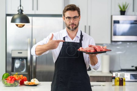 Photo for Beef steak concept. Middle aged man cooking meat, beef steak in kitchen. Man on kitchen with meat and raw beef - Royalty Free Image