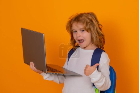 Photo for Smart child, clever school kid. School child with thumb up using laptop computer. Portrait of school boy isolated on yellow studio background. Back to school - Royalty Free Image