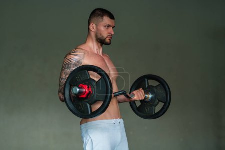 Photo for Sexy muscular man pumps his muscles and lifts barbell in gym. Strong fit man exercising with barbell. Muscular young handsome man lifting weights. Weightlifting and training with barbell - Royalty Free Image