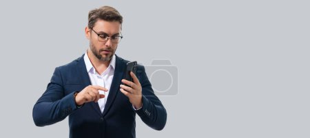 Photo for Portrait of handsome man in suit using smartphone, chatting, making post on social media. Business man call on phone isolated over studio background. Banner for header, copy space - Royalty Free Image