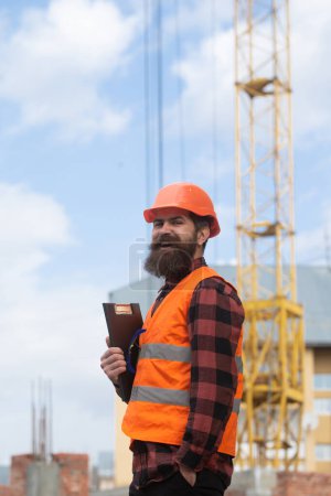 Téléchargez les photos : Homme constructeur travailleur dans casque posant sur le chantier de construction. Thème industriel - en image libre de droit
