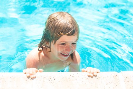 Téléchargez les photos : Un gamin nage dans la piscine. Petit garçon jouant dans la piscine extérieure dans l'eau pendant les vacances d'été. Enfant apprenant à nager dans la piscine extérieure - en image libre de droit