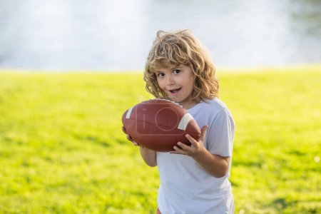Téléchargez les photos : Football américain. Portrait d'un garçon tenant un ballon de football américain dans un parc. - en image libre de droit