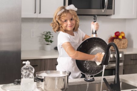 Photo for Little housekeeper. Child washing and wiping dishes in kitchen. Dishwashing liquid bottle on kitchen sink and clean plates - Royalty Free Image