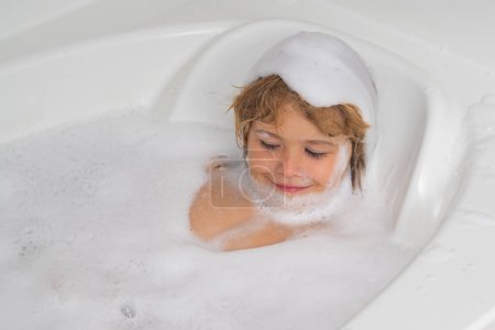 Foto de Bañera con burbuja de jabón. Niño pequeño lavándose en el baño. Retrato de niño bañándose en un baño lleno de espuma - Imagen libre de derechos