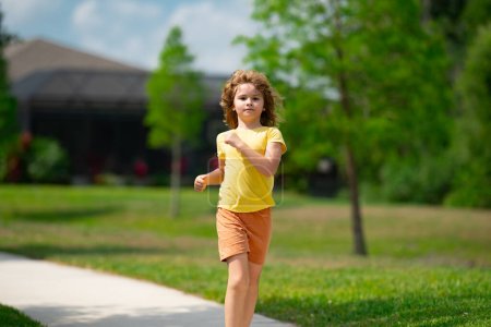 Foto de Lindo chico corriendo por la calle del vecindario americano. Verano, infancia, ocio y concepto de personas. Feliz niño rubio corriendo en el parque de verano al aire libre. Deporte y carrera - Imagen libre de derechos