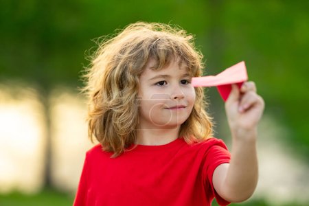 Photo for Happy kid playing with paper airplane. Cute child throwing paper plane in the park on summer day. Happy child playing with paper airplane against the sky. A boy with paper airplane. Toy airplane - Royalty Free Image
