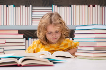Photo for Education Concept. School child studying in school library. Kid reading book in library on bookshelf background - Royalty Free Image