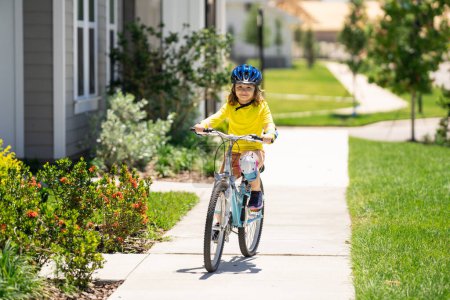 Photo for Boy in a helmet riding bike. Boy in safety helmet riding bike in city park. Child first bike. Kid outdoors summer activities. Kid on bicycle. Little child riding bike in summer park on a driveway - Royalty Free Image