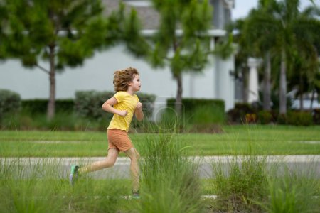 Photo for Cute kid boy running across american neighborhood street. Summer, childhood, leisure and people concept. Happy little blonde child boy running in summer park outdoor. Sport and run - Royalty Free Image