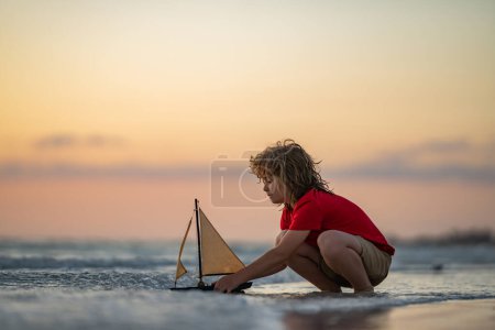 Photo for Kid playing on the beach. Child play on the sea with toy ship boat. Little child having a happy moment play with toy ship on summer beach. Kids summer vacation. Dream on travel - Royalty Free Image