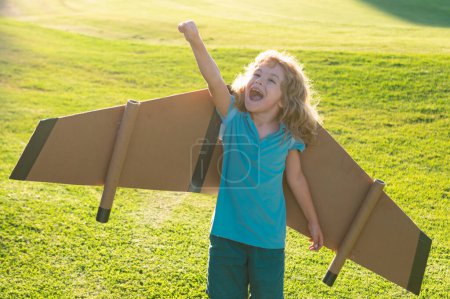 Foto de Niño jugando con alas de avión de juguete en el parque de verano. Sueña con el futuro. Un piloto de niños soñando. Concepto de sueño infantil. Rubia lindo soñador soñador niño sueño sobre la marcha. Sueños e imaginación - Imagen libre de derechos