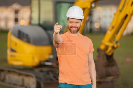 Photo for Builder with excavator for construction at the construction site. Machinery tractor with builder at buildings background. Excavator tractor and builder worker. Builder in helmet on construction site - Royalty Free Image