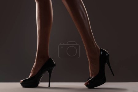 Foto de Legs of young sexy sensual slim woman in high heeled shoes on studio background. Womens legs with heels shoes. Trendy fashion high heeled shoes. Summer look with high heels. Classic high heels - Imagen libre de derechos