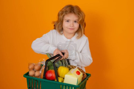 Foto de Tienda de comestibles. Retrato de niño con cesta de la compra comprando comida en una tienda de comestibles en un estudio aislado fondo - Imagen libre de derechos