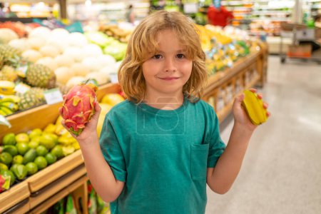 Foto de Niño con frutas. Comida saludable para niños. Retrato de niño sonriente con bolsa de compras en la tienda de comestibles o supermercado - Imagen libre de derechos