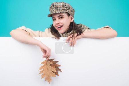 Téléchargez les photos : Hipster jeune femme en tenue d'automne tendance chapeau élégant et écharpe. Beauté fille tenir feuilles d'automne près du visage, isolé sur fond de studio. Portrait de femme automnale à la feuille d'érable - en image libre de droit