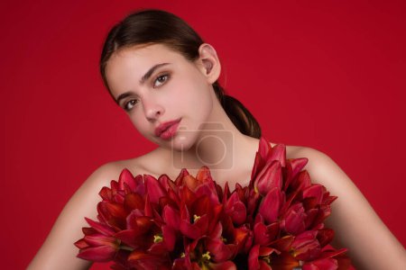 Foto de Chica de belleza con tulipán. Hermosa mujer sensual mantenga tulipanes ramo, retrato de estudio sobre fondo rojo - Imagen libre de derechos