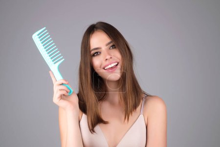 Photo for Woman combing her hair. Cares about a healthy and clean hair. Beauty hair salon concept. Girl with a comb in studio. Brushing hair, smooth soft silky hairs effect keratin. Hairs brush - Royalty Free Image