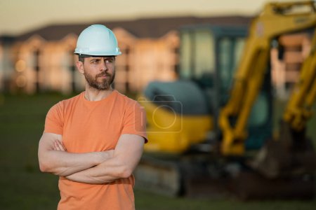 Photo for Construction man with excavator at industrial site. Worker in helmet build with bulldozer. Engineer work with builder contractor in hardhat. Excavation foreman with tractor. Workman with excavator - Royalty Free Image