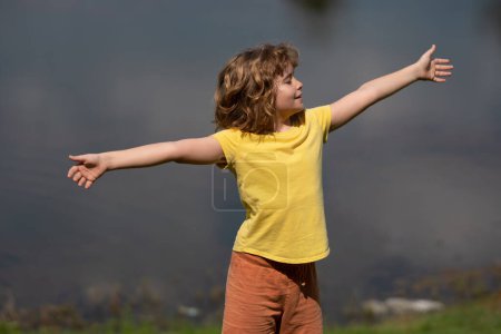 Téléchargez les photos : Enfant heureux avec les bras levés jouissant de la liberté dans la nature. Enfant à bras ouverts médite. Enfant jouissant de la liberté levant les bras. Sentiments d'enfant de liberté dans la nature. Enfant dans la nature estivale. Calme relax - en image libre de droit