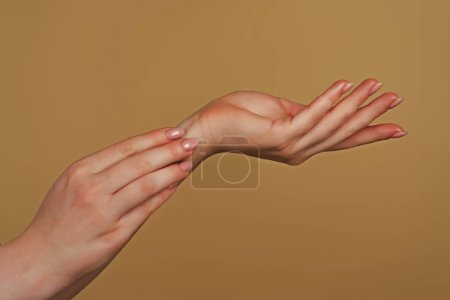 Foto de Hermosas manos de mujer. Las manos femeninas aplicando crema, Loción. Concepto de spa y manicura. Manos femeninas con manicura francesa. Piel suave, concepto de cuidado de la piel. Cuidado de la piel de las manos. Las manos de la mujer tratan de tocar - Imagen libre de derechos