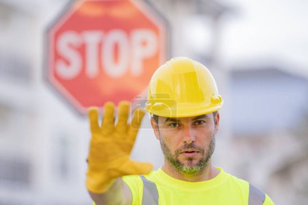 Photo for Builder showing STOP. Serious builder with stop road sign. Builder with stop gesture, no hand, dangerous on building concept. Man in helmet showing stop road sign - Royalty Free Image