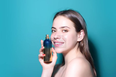 Photo for Woman with perfume bottle in studio. Girl with perfume, young beautiful woman holding bottle of perfume and smelling aroma. Sensual model with perfumes. Beauty perfume. Cologne bottle and perfumery - Royalty Free Image
