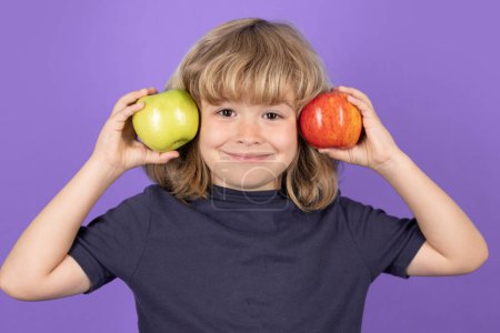 Photo for Funny kid boy hold a red apple and a green apple. Isolated on studio background - Royalty Free Image