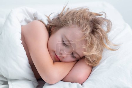Foto de Mañana de sueño. Hermosa cara de niño rubia caucásica, durmiendo en la cama. Dulces sueños. Pequeño niño durmiendo tumbado en la cama en casa - Imagen libre de derechos