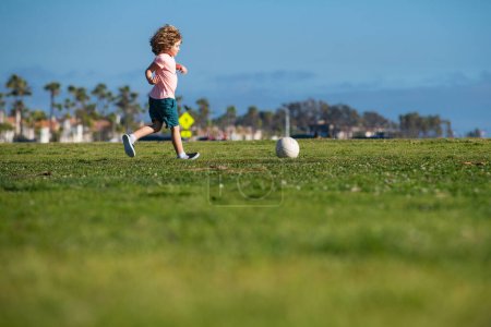Foto de Niño jugando al fútbol, niño feliz disfrutando del juego de fútbol deportivo, actividades infantiles, pequeño jugador de fútbol. Niños entrenando fútbol - Imagen libre de derechos