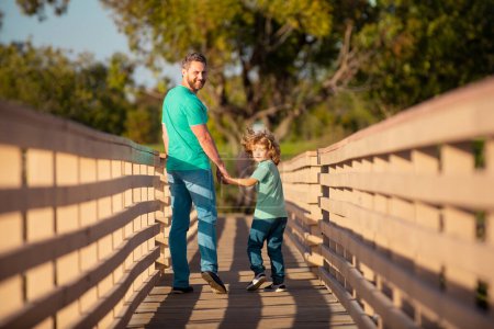 Photo for Father with son walking on wooden bridge outdoor - Royalty Free Image