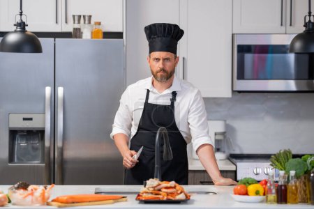 Photo for Portrait of cook man preparing fresh salmon at kitchen. Handsome man in cook apron and chef hat preparing raw fish salmon. Chef cooking seafood in kitchen. Millennial man hold raw fish salmon - Royalty Free Image