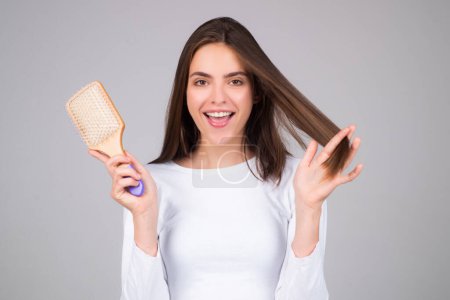 Photo for Girl combing hair with comb. Beautiful young woman holding hair comb. Female model hold comb near face. Woman portrait with comb - Royalty Free Image