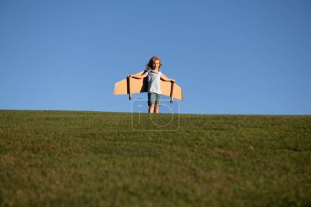Téléchargez les photos : Enfant garçon rêve et voyage. Garçon avec jouet d'avion à l'extérieur. Joyeux enfant jouant avec l'avion jouet dans le champ d'été sur le ciel. Voyage, vacances et concept de liberté - en image libre de droit