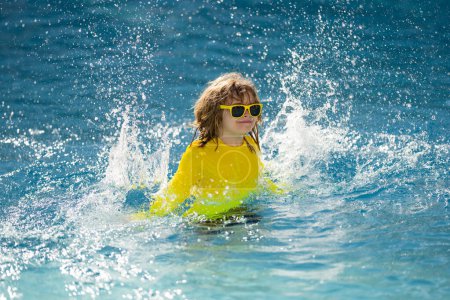 Photo for Excited child swimming. Little kid playing in blue water of swimming pool on a tropical resort at the sea. Cute boy swimming in pool water. Child splashing and having fun in swim pool - Royalty Free Image