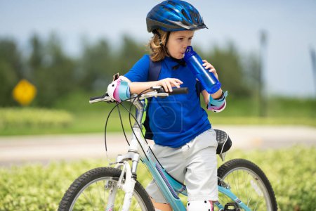 Photo for Child on bicycle. Boy in a helmet riding bike. Little cute caucasian boy in safety helmet riding bike in city park. Child first bike. Kid outdoors summer activities. Kid on bicycle. Boy ride a bike - Royalty Free Image