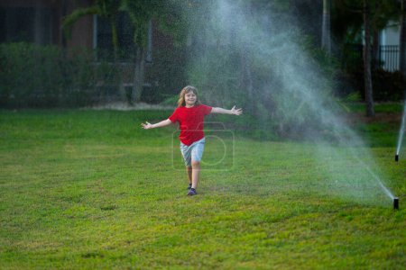 Photo for Kids play with water hose, sprinkler watering grass in the garden. Summer garden outdoor fun for children. Boy splashing water on hot summer day. Kid watering plants and grass in backyard - Royalty Free Image