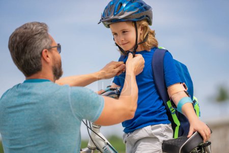Photo for Happy family. Father and son riding bike in park. Child in safety helmet with father riding bike in summer day. Father helping his son to wear a cycling helmet. Child in safety helmet - Royalty Free Image