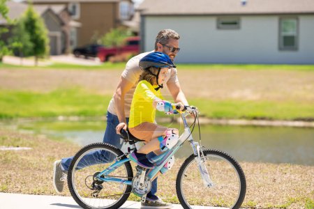 Photo for Fathers day. Boy learning to ride a bicycle with his father in park. Father teaching his son cycling on bike. Father learn little son to ride a bicycle. Father support child. Fathers day background - Royalty Free Image