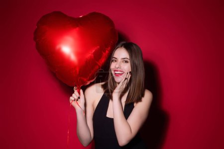 Photo for Beautiful young woman holding red heart shaped baloons, valentines day. Romance date of sexy woman. Woman celebrating Valentines Day. Portrait pretty woman with red balloon heart shape - Royalty Free Image