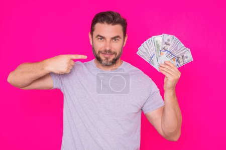 Foto de Guapo hombre de mediana edad americano sosteniendo dinero aislado en un estudio rosa. Dinero en billetes de dólar. Montón de efectivo, finanzas, inversión y ahorro de dinero. Mockup banner, concepto de pago - Imagen libre de derechos