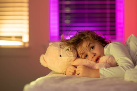 Téléchargez les photos : Portrait de petit enfant couché sur grand lit. Cauchemar pour les enfants. Concept d'enfants heureux passer une bonne nuit. Somnolence infantile au lit - en image libre de droit