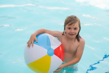 Téléchargez les photos : Petit garçon dans une piscine avec un ballon de plage. Joyeux enfant qui s'amuse en vacances d'été. Enfant jouant avec la balle dans la piscine. Jeu d'enfant avec boule flottante dans l'eau de mer - en image libre de droit