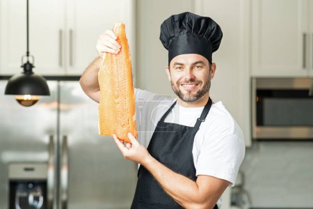 Photo for Man in modern kitchen, preparing healthy food fish salmon. Handsome man is cooking fresh fish salmon beef in the kitchen at home - Royalty Free Image