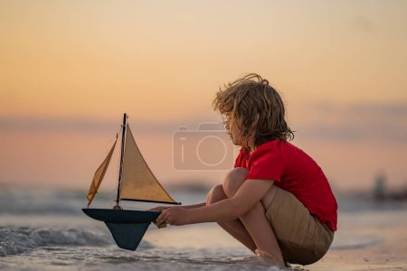 Photo for Little kid boy sailing toy ship on sea water. Summer vacation with kids. Kid dreaming about sailing. Concept of childhood and family vacation. Adventure and travel with children - Royalty Free Image