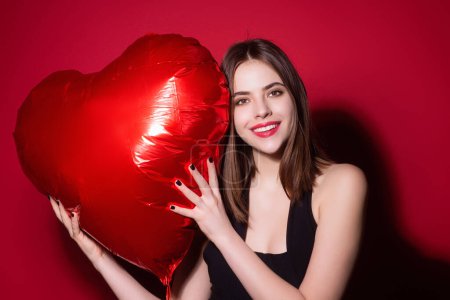 Foto de Día de San Valentín, corazón de amor. Retrato de la encantadora chica de San Valentín con el corazón rojo. Hermosa mujer celebrar el día de San Valentín. Mujer enamorada. Una mujer en la fiesta de San Valentín. Símbolo del amor. Tarjeta San Valentín - Imagen libre de derechos