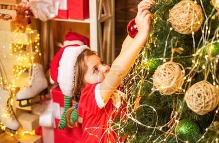 Téléchargez les photos : Jouet de Noël - fille décore le sapin de Noël. Enfant de Noël décorant arbre de Noël avec boule - en image libre de droit