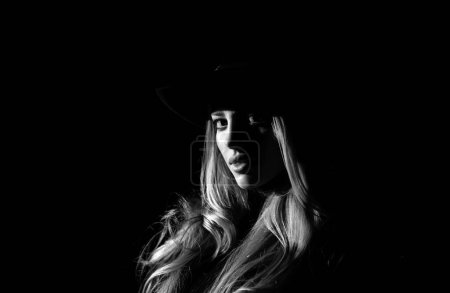 Photo for Sexy gorgeous woman with shadows on beautiful face and fashion hat on black studio. Fashion portrait of beautiful woman with dark light on face - Royalty Free Image